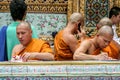 Buddhist monk writing the letter and speaking phone. Group of Buddhist monks walking around Grand Palace complex. Royalty Free Stock Photo