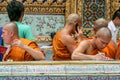 Buddhist monk writing the letter and speaking phone. Group of Buddhist monks walking around Grand Palace complex. Royalty Free Stock Photo