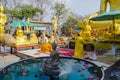 Buddhist monk in yellow dress prays in front of Buddha statue in temple