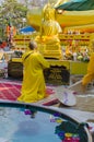 Buddhist monk in yellow dress prays in front of Buddha statue in temple