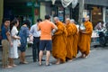 Buddhist monks collect food on a city street. Bangkok