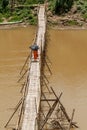 Buddhist monks cross the Nam Khan river on a bamboo bridge, protecting themselves from the sun with umbrellas, Luang Prabang, Laos Royalty Free Stock Photo