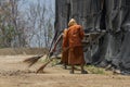 Buddhist monks sweeping courtyard in temple in Thailand