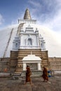 Buddhist monks walk around the Ruwanwelisiya Dagoba (Ruvanvelisaya) at Anuradhapura in Sri Lanka.