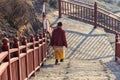 Buddhist nun walking down stairway at Larung gar in a warm and foggy morning time
