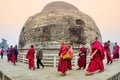 Buddhist pilgrims dressed in red is walking clockwise around the Dhamekh Stupa