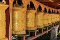 Buddhist prayer wheels in a row in a Tibetan monastery Royalty Free Stock Photo
