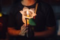 Buddhist praying with incense sticks, lotus flower and candles on holy religion day of Vesak at night.