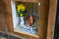 Buddhist Shrine with Flowers, Liquor in Ceramic Cups and a Small Statue of the God of Money at a Cafe in Vietnam Royalty Free Stock Photo