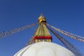 Buddhist Tibetan white stupa temple  Bodnath in Kathmandu with multicolored prayer flags against a clean blue sky Royalty Free Stock Photo