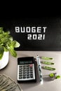 2021 Budget concept with letters on black background and blurred calculator, pins, dollars