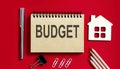 BUDGET text written on a notebook with pencils and office tools and model wooden house Royalty Free Stock Photo