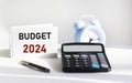 BUDGET 2024 written on a notepad and white background and with a calculator clock Royalty Free Stock Photo