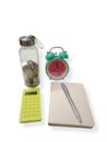 Budgeting setup with coin jar, alarm clock, calculator, notebook, and pen, representing financial planning. Royalty Free Stock Photo