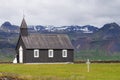 Unidentified bride and groom standing in front of Famous black church in Budir, Iceland.