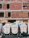 Budva, Montenegro - 05 august 2023: Overflowing trash cans stand next to a house under construction