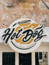 Budva, Montenegro - 08 august 2023: Round signboard for a cafe on an old stone facade of a house. Caption: Hot dog