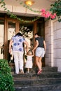 Budva, Montenegro - 13.08.2022: Grandmother and mother lead a little girl holding her hands up the stairs to the door of Royalty Free Stock Photo