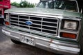 Close-up of radiator grille, headlights, hood and chrome bumper with rust of Ford F-100 pickup truck