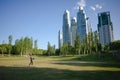 Young man playing baseball game in a city park near high office buildings