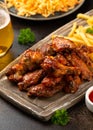 Buffalo chicken wings with beer, french fries on wooden board. fast food