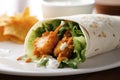 A close-up view of a crispy and spicy buffalo chicken wrap served on a plate. (Generative AI) Royalty Free Stock Photo