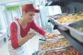 Buffet female worker servicing food in cafeteria