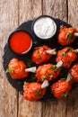 Buffet menu of Lollipops deep-fried red chicken wings served with sauces close-up on a slate board. Vertical top view Royalty Free Stock Photo