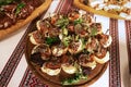 A buffet with a plate of appetizers of sandwiches with fish, salty cucumber and lemon, combined with spatulas, embroidered tablecl