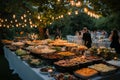 Buffet table illuminated by string lights at an evening outdoor wedding reception Royalty Free Stock Photo