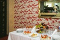Buffet table near the wall with colored wallpaper and a large mirror
