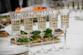 buffet table, white tablecloth, champagne glasses on a long stem. Carbonated white wine. Selective focus, plates and snacks. The