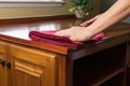 buffing a wooden cabinet with a microfiber cloth