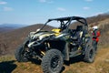 Buggy parked in mountains and driver in sport equipment standing behind