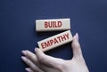 Build empathy symbol. Wooden blocks with words Build empathy. Psychologist hand. Beautiful deep blue background. Psychology and Royalty Free Stock Photo