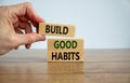 Build good habits symbol. Wooden blocks with words `build good habits`. Male hand. Beautiful wooden table, white background, cop