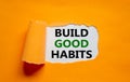 Build good habits symbol. Words `Build good habits` appearing behind torn orange paper. Beautiful orange background. Business,