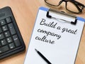 Build a great company culture written on paper clipboard with a pen.