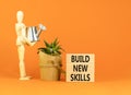 Build new skills symbol. Concept word Build new skills on beautiful wooden block. Businessman model. Beautiful orange table orange