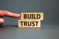 Build trust symbol. Concept words Build trust on wooden blocks on a beautiful grey table grey background. Businessman hand. Royalty Free Stock Photo