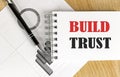BUILD TRUST text on notebook with chart on wooden background Royalty Free Stock Photo