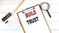 BUILD TRUST words on clipboard, with calculator, magnifier and pencil on the white wooden background Royalty Free Stock Photo