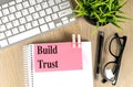 BUILD TRUST text pink sticky on notebook with keyboard, pen and glasses Royalty Free Stock Photo