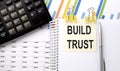 BUILD TRUST text, written on a sticker with calculator,pen on chart background Royalty Free Stock Photo