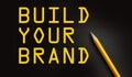 BUILD YOUR BRAND words on black with yellow pencil besides. Branding rebranding marketing business startup concept