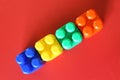 Buildable colored plastic blocks to play, build and organize on a red background as a concept of inclusion, diversity and pluralit Royalty Free Stock Photo