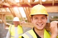 Builder And Apprentice Carrying Wood On Construction Site Royalty Free Stock Photo