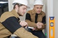 Builder and apprentice inspecting level
