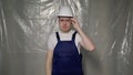 Builder in blue overalls puts on white hard hat helmet Royalty Free Stock Photo