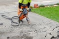 Builder breaking asphalt with hydraulic jackhammer